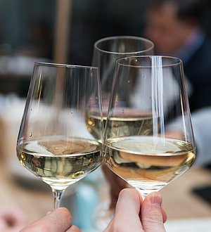 Drei Gläser mit Weißwein stoßen an 